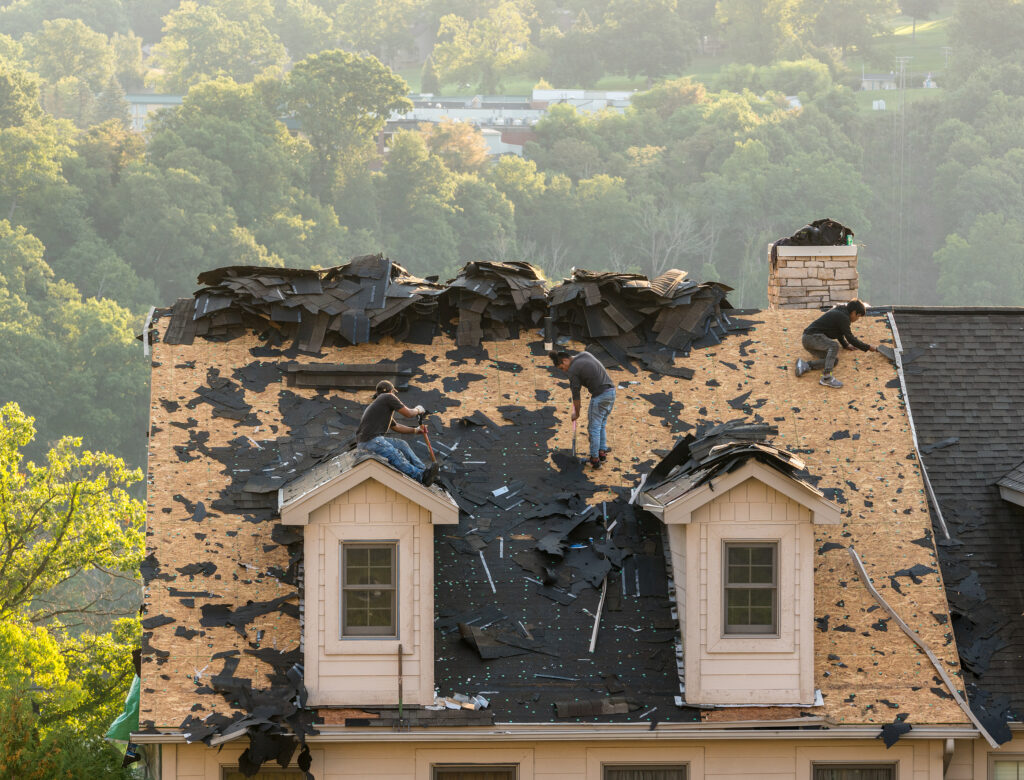 Roofer in Chesterfield, MO, removing the old tiles from townhouse roof before replacing with new shingles
