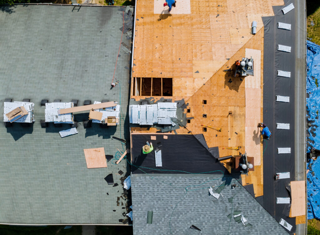 A Webster Groves roofer nailing shingles with air gun, replacing roof cover protection being applied, apartment development